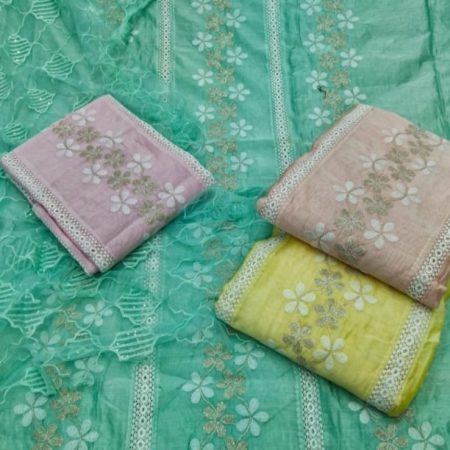 A display of vibrant Chanderi fabrics featuring floral patterns in pastel shades of pink, yellow, and a green backdrop with intricate embroidery.